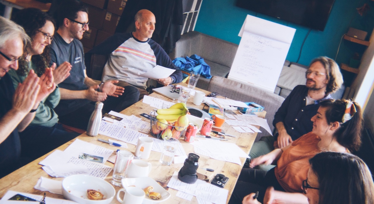 Clearleft team sat round a wooden table, smiling and applauding.